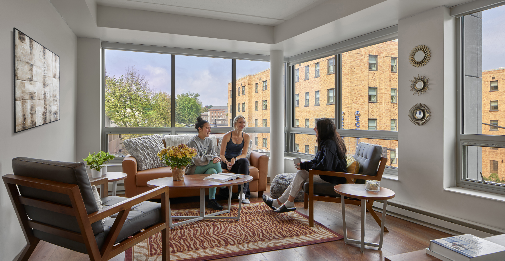 Three roommates chatting in the living room of their shared multifamily apartment.